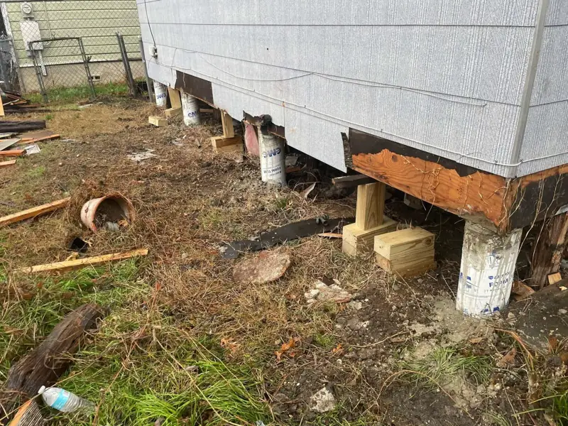 Raised house during pier and beam repair, sitting on new concrete piers with temporary wood cribbing
